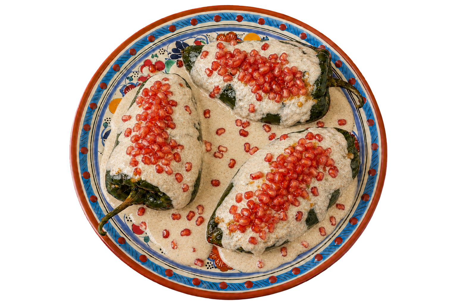 Tres chiles en nogada con granada sobre un plato de Talavera